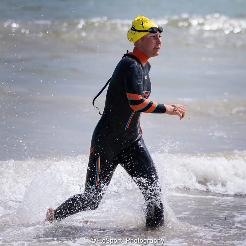 Une femme en combinaison de nage marche vers la plage.