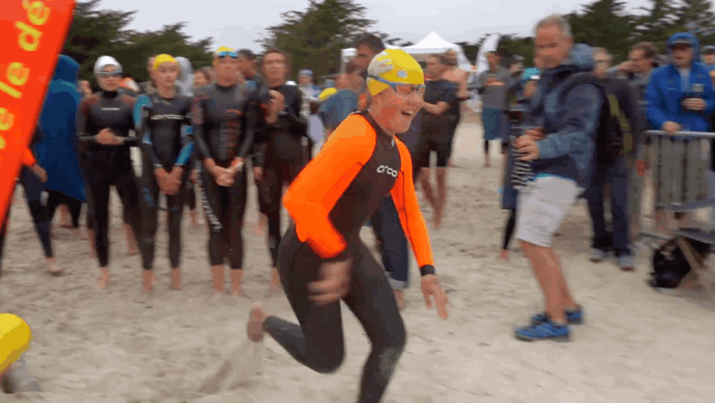 Un jeune garçon en combinaison de nage qui court sur la plage.