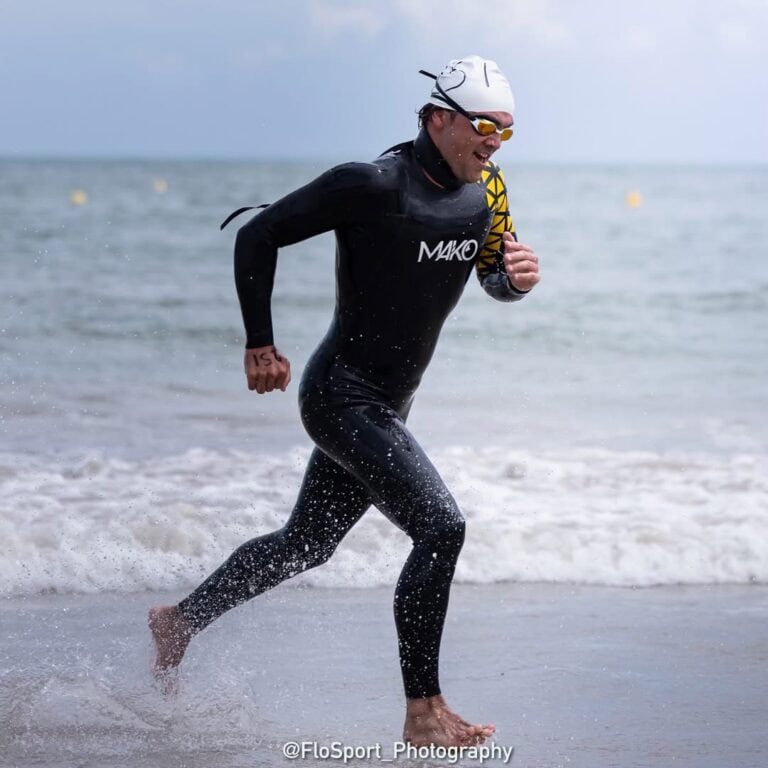 Un homme en combinaison de nage sort de l'eau en courant